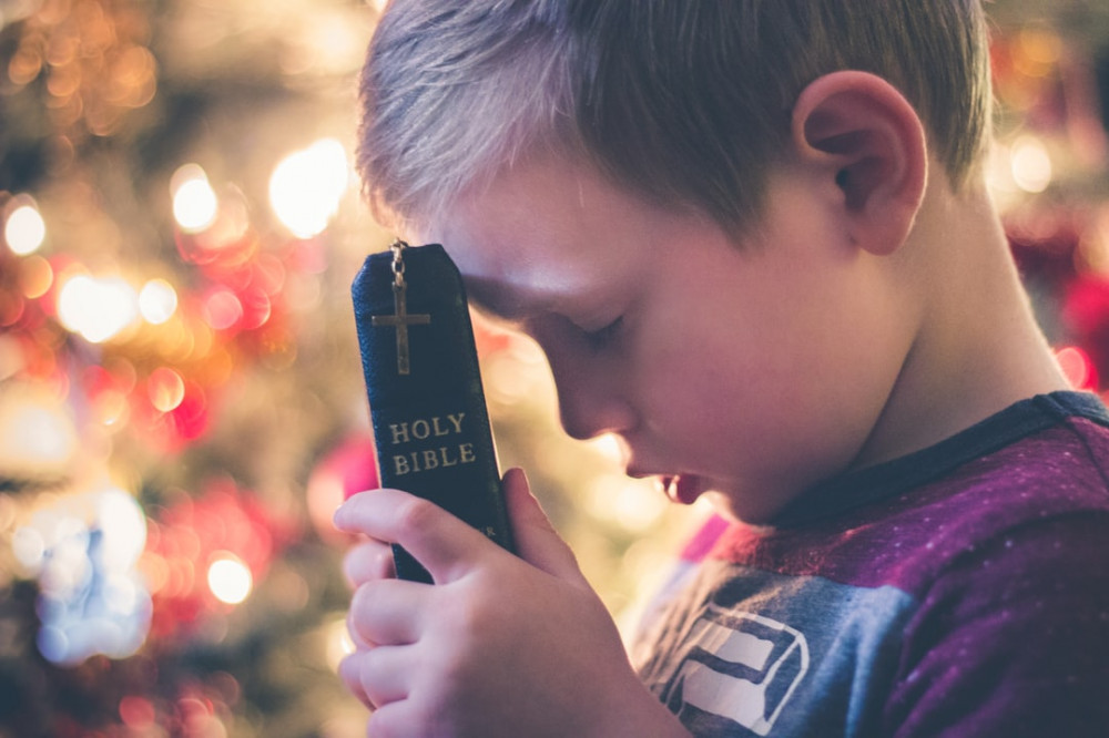 Boy Praying Holding the Holy Bible