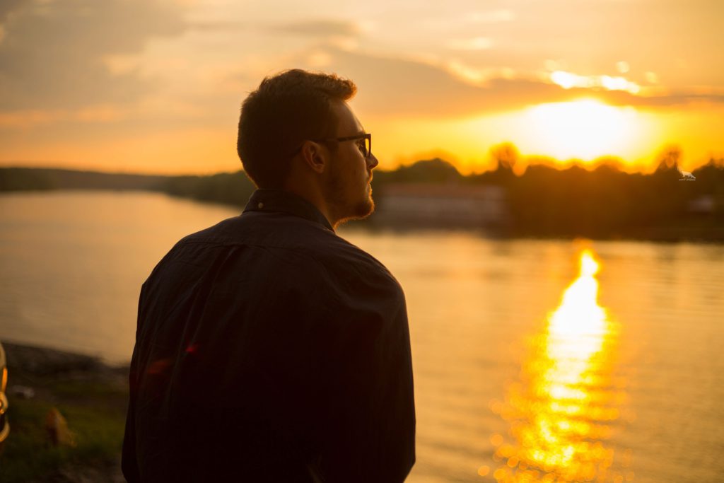 Guy Sitting by River Facing Sunset