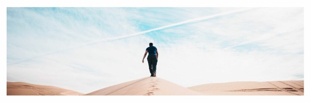 Man Walking in the Middle of Desert with Blue Sky