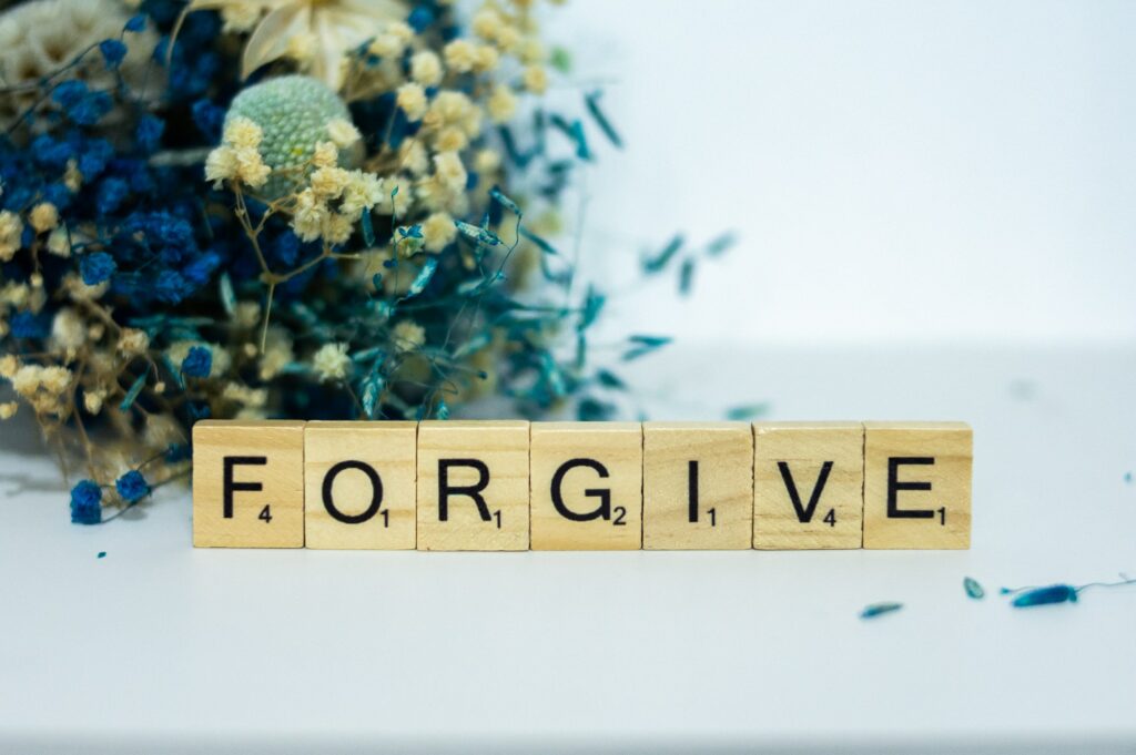 Scrabble Word Forgive and Flower Decoration on the Table